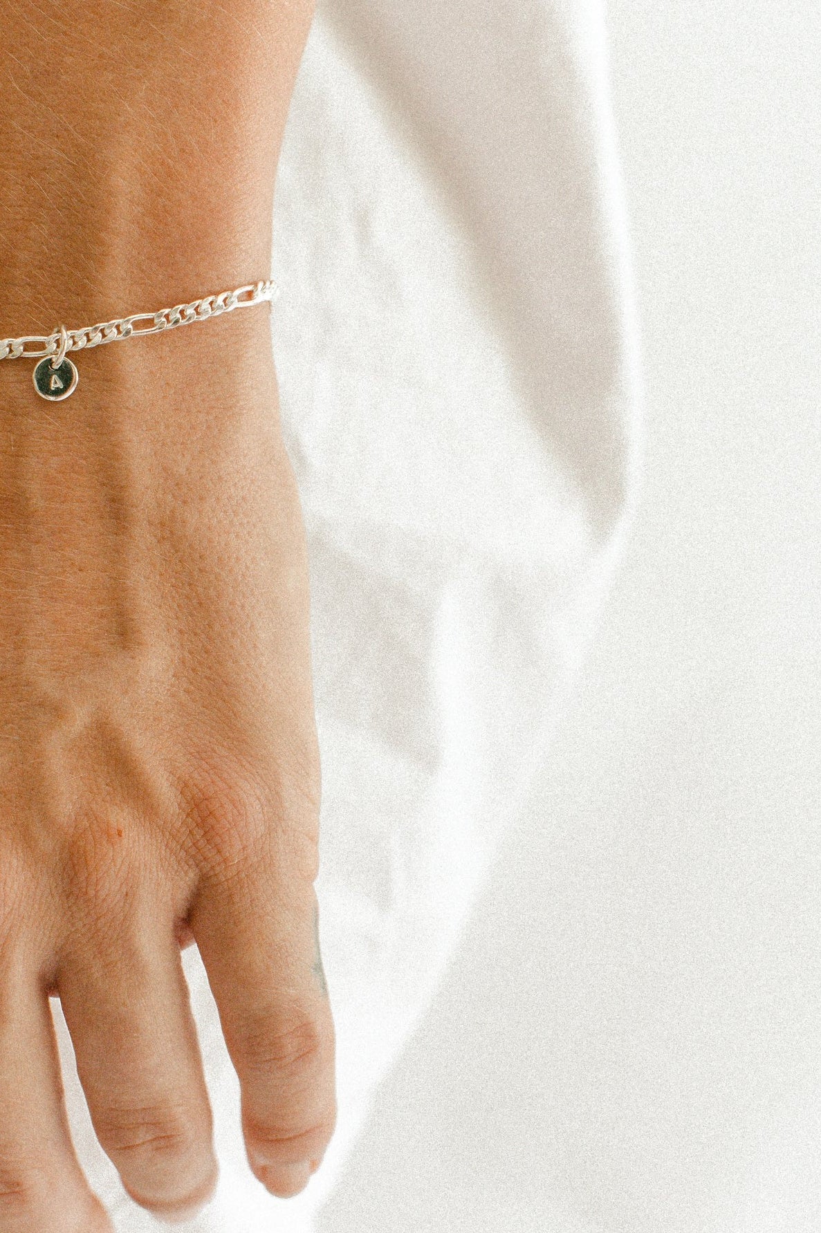 A Figaro Bracelet in adult length worn with one 6mm initial pendant by Bluebird Jewellery