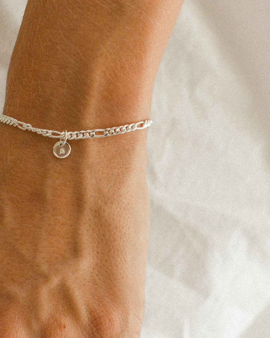 A Figaro Bracelet in adult length worn with one 6mm initial pendant by Bluebird Jewellery