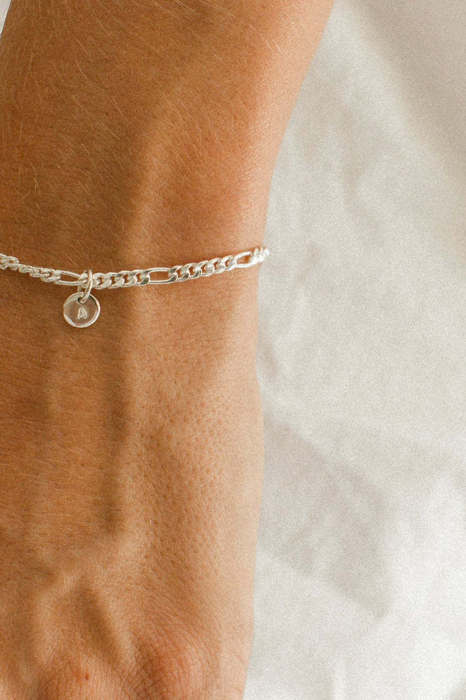 A Figaro Bracelet in adult length worn with one 6mm initial pendant by Bluebird Jewellery