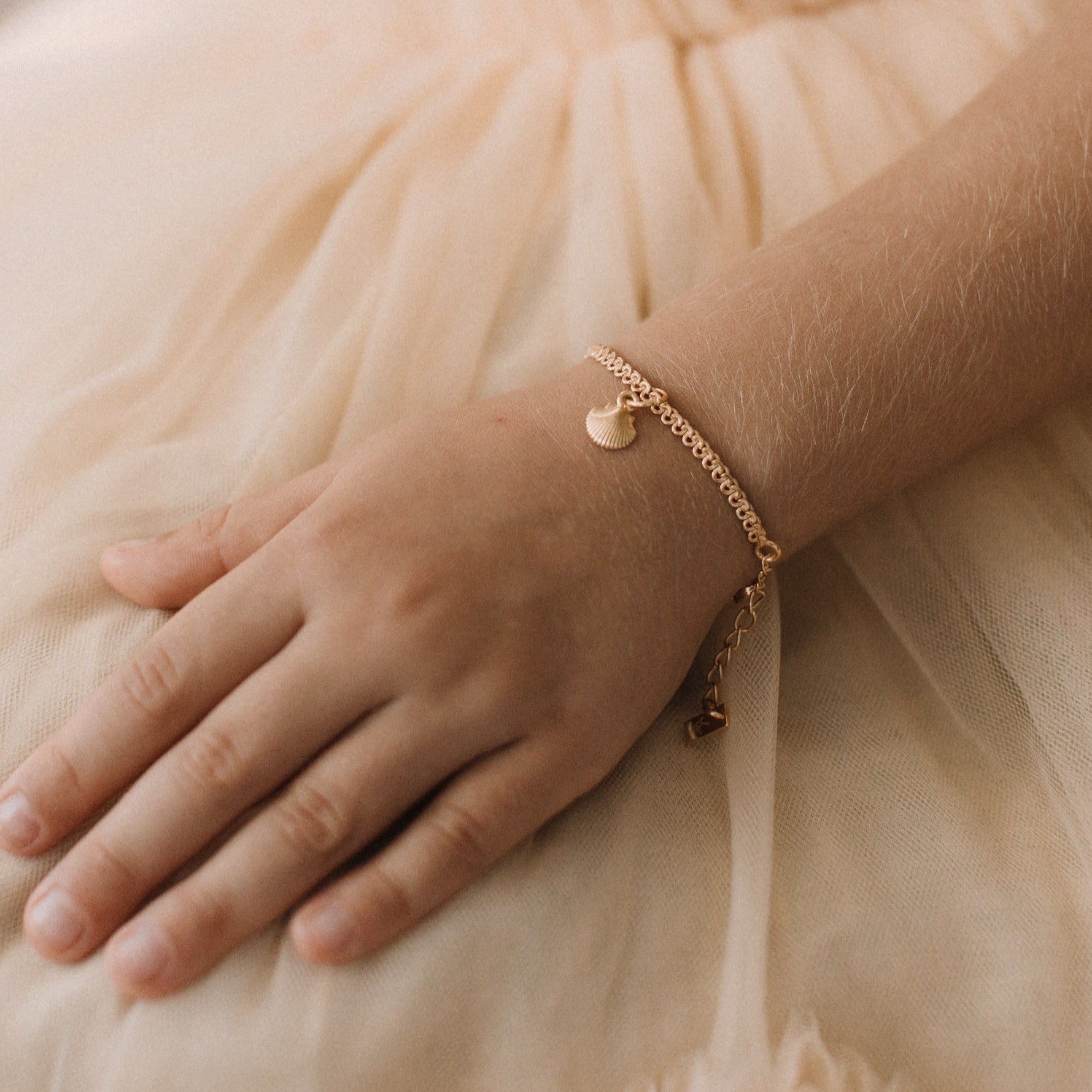 A delicate Lace Chain bracelet with a mermaid shell charm, designed as elegant fine jewellery by Bluebird Jewellery
