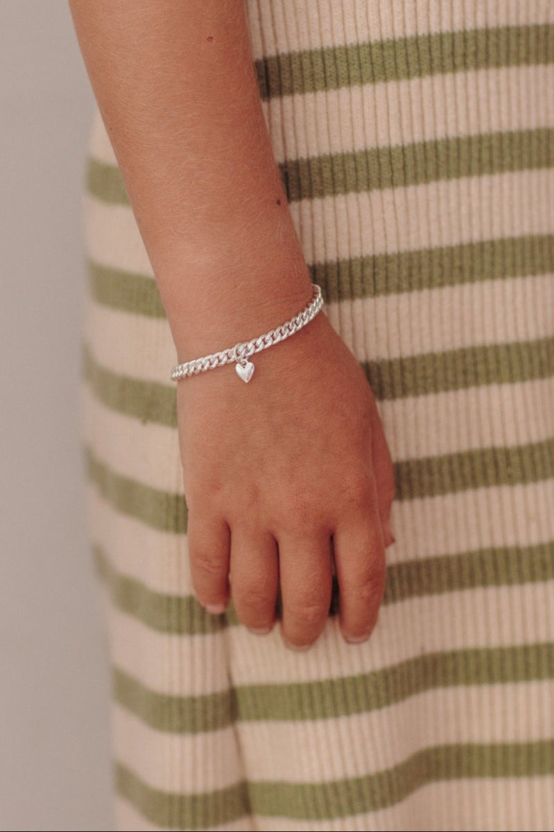 sterling silver cuban link bracelet with a mini sweetheart pendant in sterling silver sits effortlessly on child's wrist by Bluebird Jewellery
