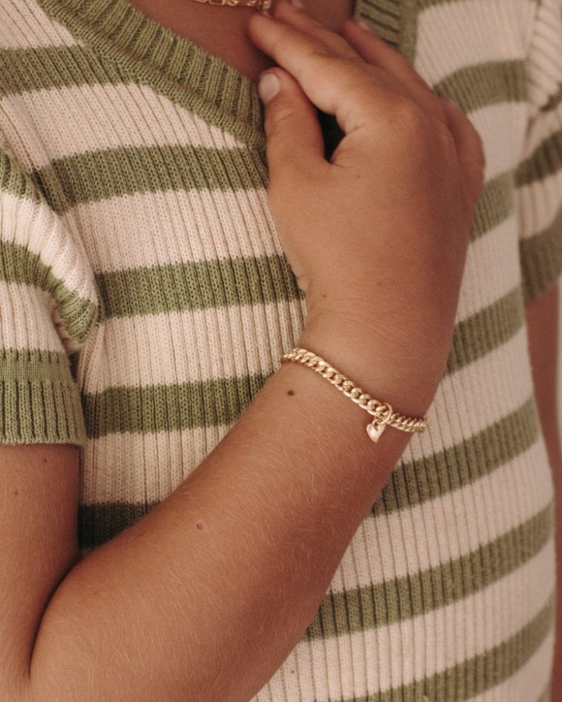 A young girl wearing a gold Sweetheart Cuban Link Chain and polished heart pendant, designed as a timeless keepsake piece.
