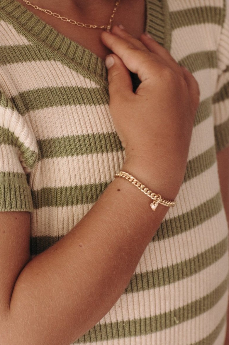A young girl wearing a gold Sweetheart Cuban Link Chain and polished heart pendant, designed as a timeless keepsake piece.