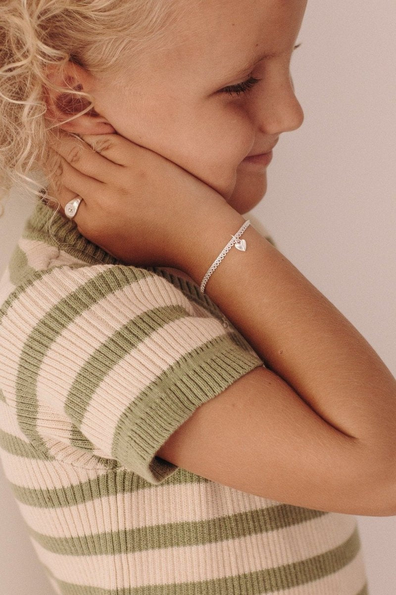 A detailed close-up of a young girl wearing a gold silver Sweetheart Lace Chain and signet ring, crafted as elegant fine jewellery pieces.