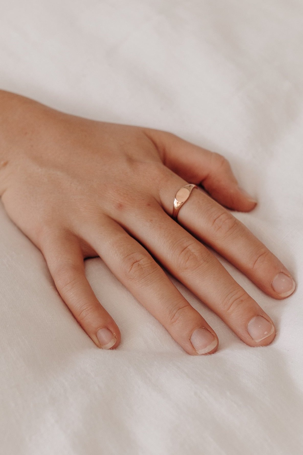 Adult signet ring in solid rose gold.  A close up image of the ring on a woman's hand.