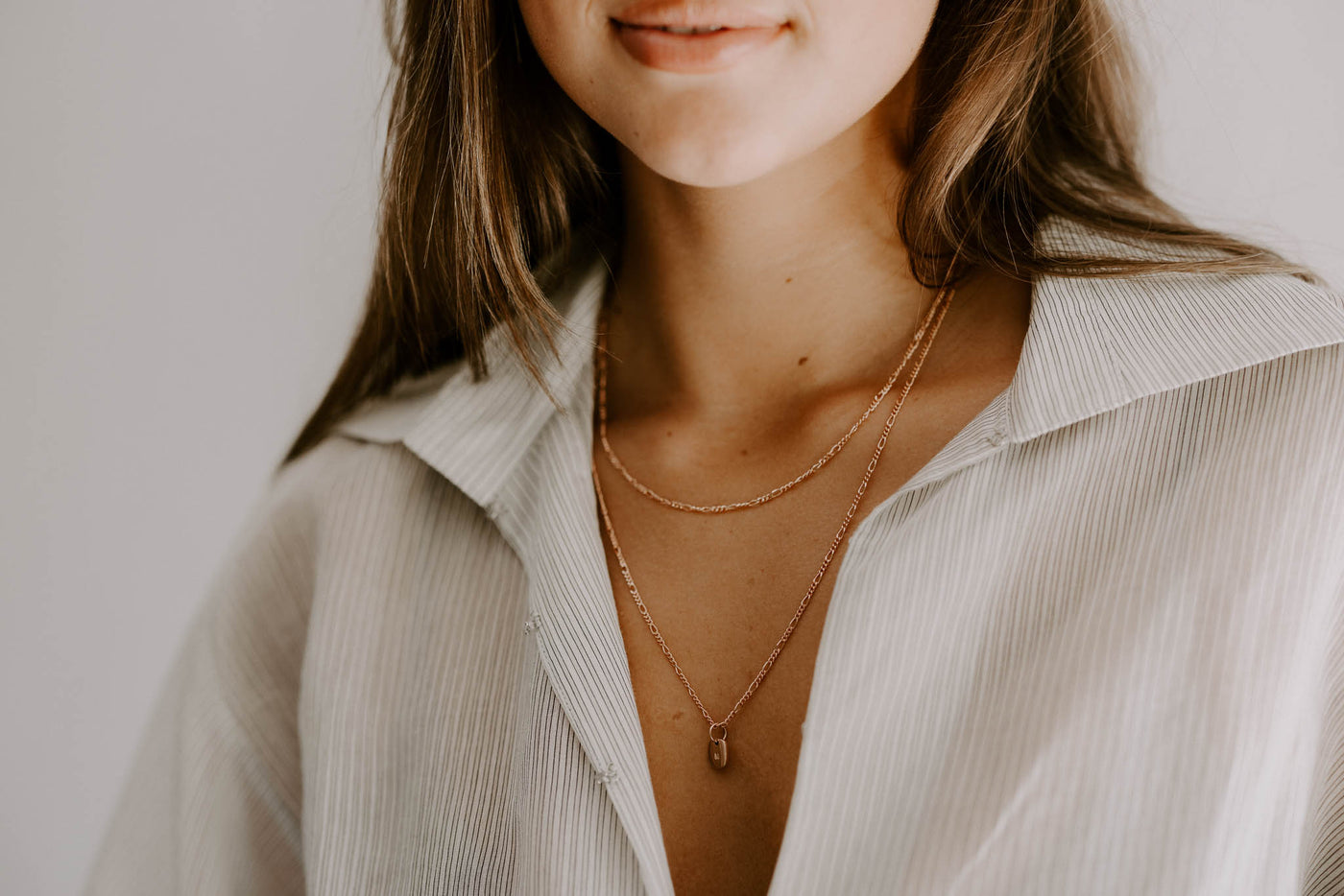 A woman is wearing a 45cm Figaro Necklace with a 55cm Figaro Necklace with a Rectangular Pendant