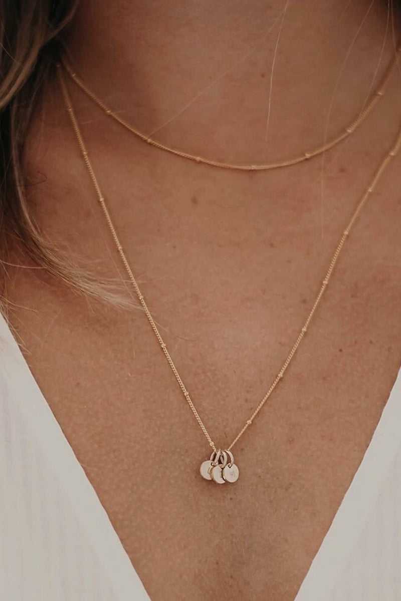 Beautifully petite solid gold personalised pendants hang on a gold plated necklace. The necklace is layered with a shorter gold plated necklace giving a lovely layered look.