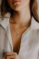 A woman wears a Rose Gold Petite Personalised Necklace layered with a 35cm Rose Gold Ball Chain Necklace for an effortless personalised layered necklace look with an open collared light-weight shirt.