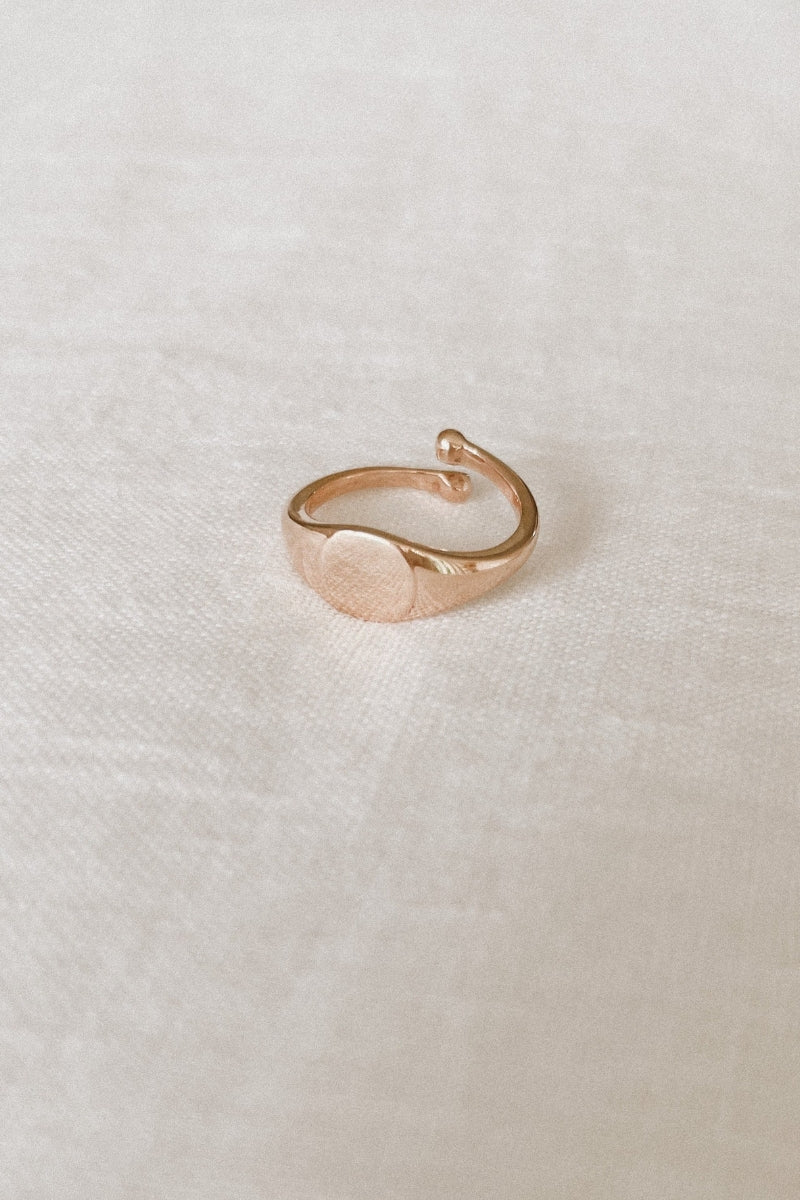 Solid 9ct Gold Signet ring sitting on white linen.  The image shgows the adjustable sides on the child sized ring.