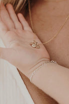 A child is holding her mother's necklace pendants in the palm of her hand.  They are solid gold initial pendants that remind the mother of her children.