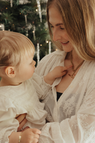A woman is wearing a chunky fob necklace and her daughter is looking at it on her.
