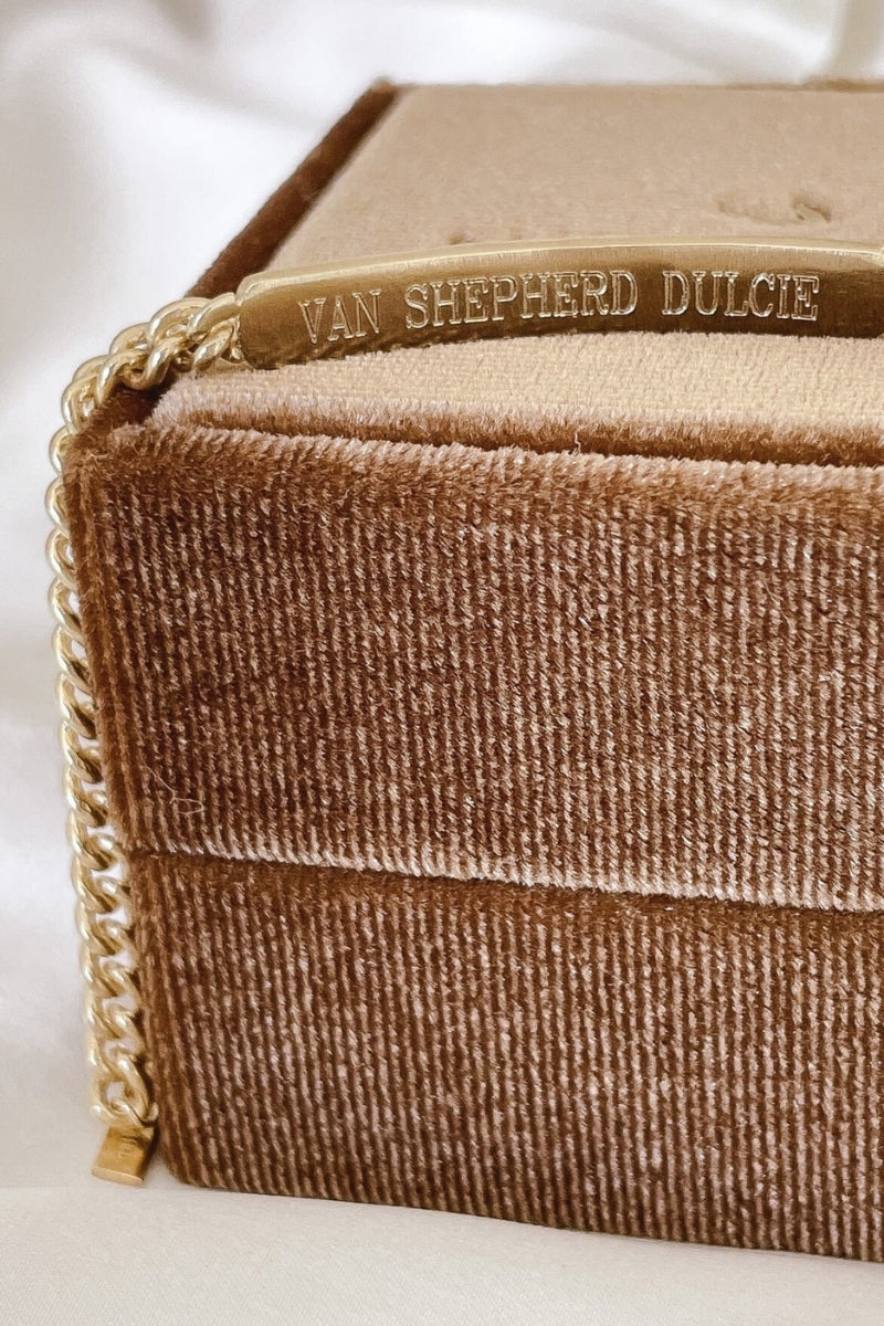 A close up image of the engraving on the back of a Signature Bracelet as it is draped over a velvet gift box.  three children's names are engraved into the back of the bracelet.