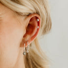 A woman is wearing 4 earrings in her ear.  The Petite Vintage Pearl Earring is on the earlobe alongside the Petite Daisy Hoop earring.