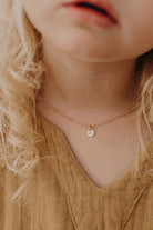 A young girl is wearing a personalised keepsake necklace with a solid rose gold initial pendant on a beautifully delicate rose gold plated ball chain necklace.