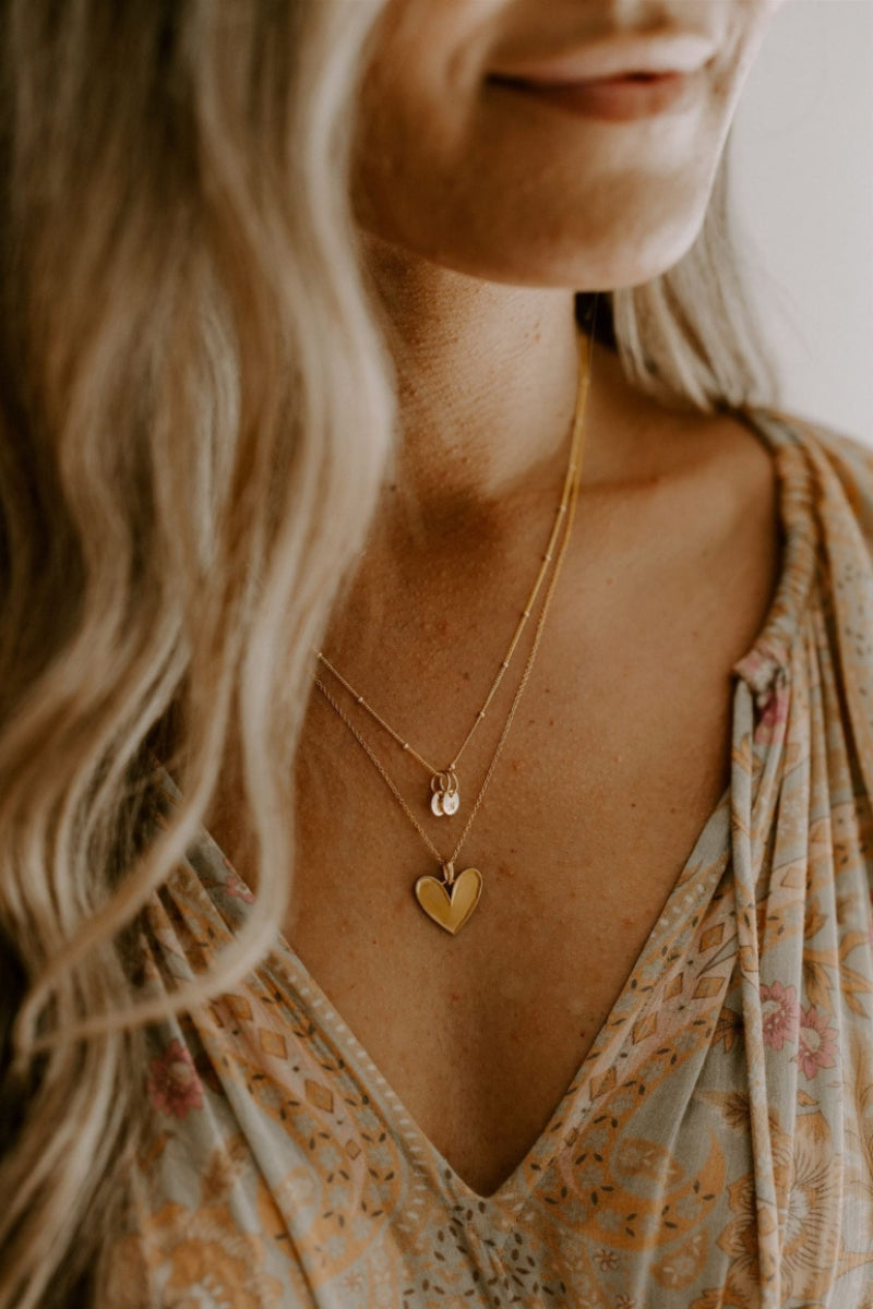 A woman wears the Gold Petite Personalised necklace layered with the Gold Darling necklace 