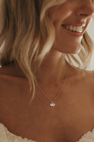 Woman wearing a delicate necklace with a initial pendants.