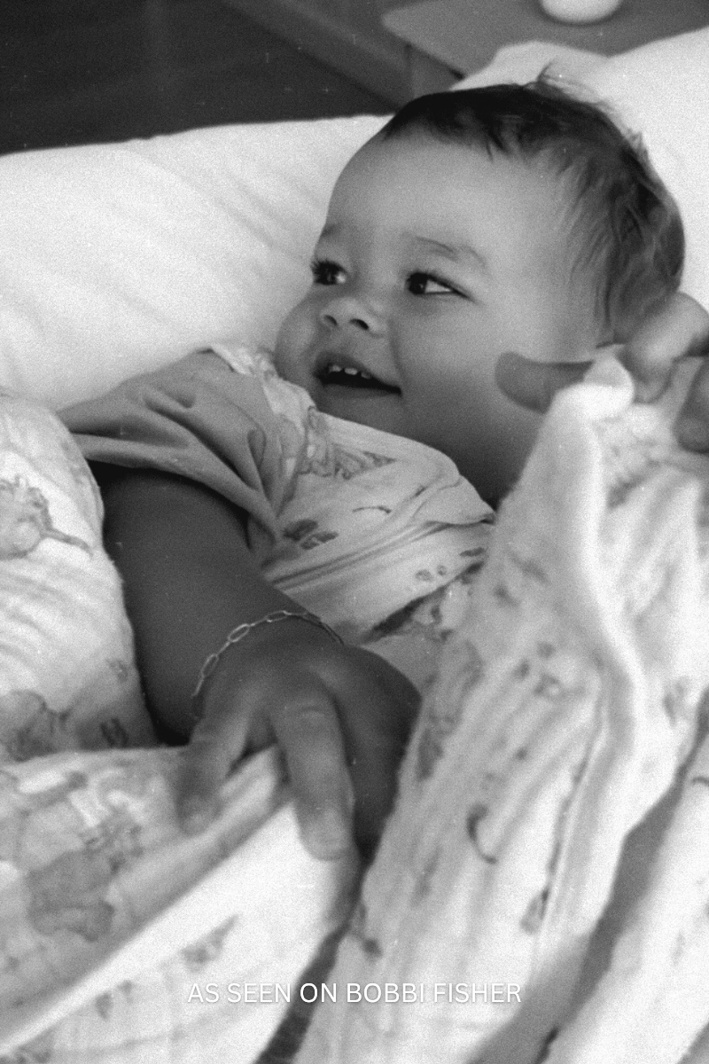 Black and white photo of Bobbi Fisher lying on a soft surface with Posie Bracelet. 