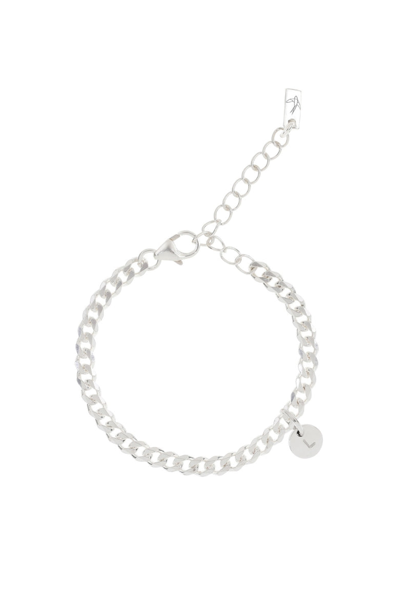 A minimalist silver anklet with a round engraved pendant, photographed on a white background to showcase its craftsmanship and simplicity.