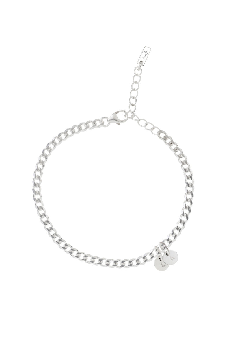 A minimalist silver anklet with round engraved pendants, photographed on a white background to showcase its craftsmanship and simplicity.