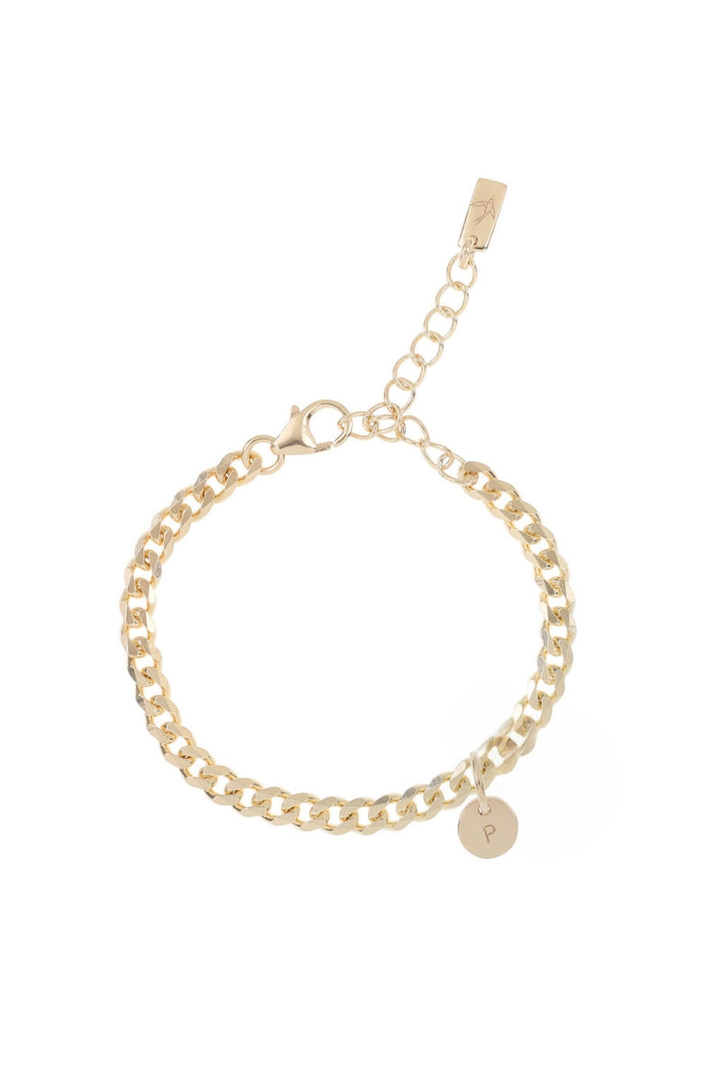 A close-up of a gold anklet with engraved initial pendant, designed as a simple and elegant everyday piece.