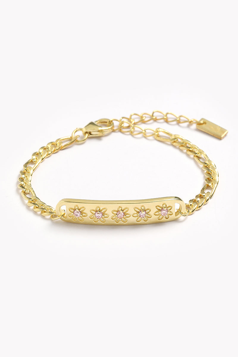 A Gold Daisy bracelet with 5 pink cubic zirconias set within each daisy on the bar pendant of the bracelet by Bluebird Jewellery.