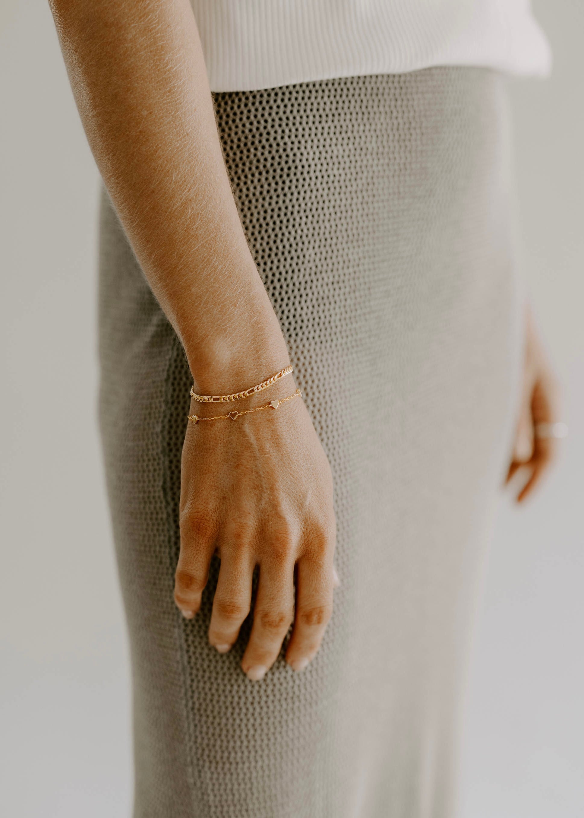 A woman wearing a Darling Heart Bracelet by Bluebird Jewellery, crafted with five petite hearts for a sweet and timeless look, perfect alongside your Bluebird Co collection.