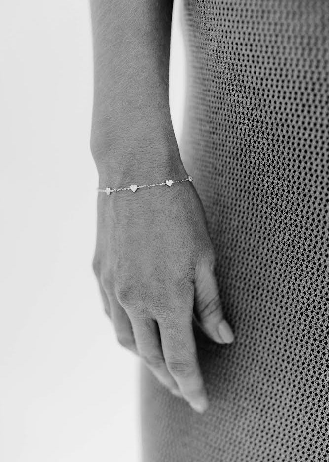 A woman wearing a Darling Heart Bracelet in Silver by Bluebird Jewellery, crafted with five petite hearts for a sweet and timeless look, perfect alongside your Bluebird Co collection.