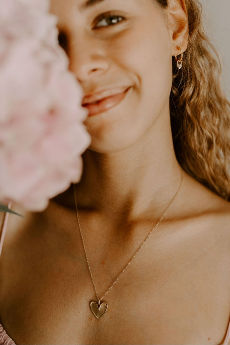 A teenage girl is wearing the Darling Necklace paired with her You Are Loved Earrings both in gold vermeil.