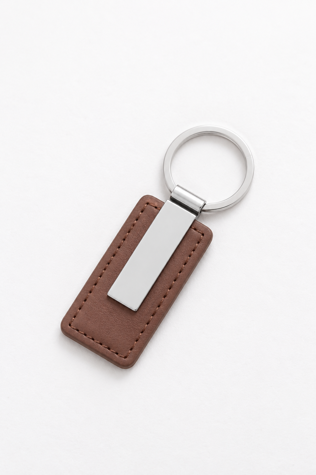 A brown leather keychain tag with a silver metal plate and a silver key ring, shown on a clean white background.