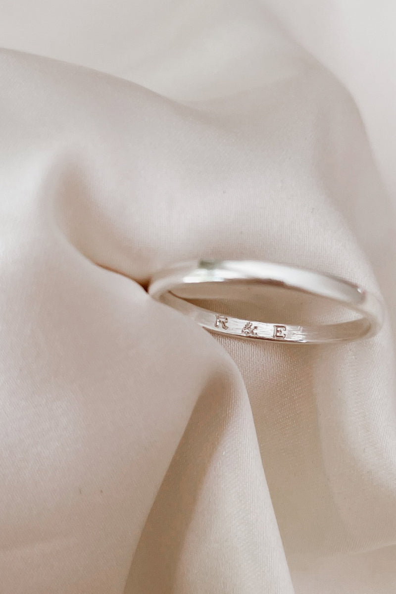 the inside of a pinky ring with the engraving of initials is shown.