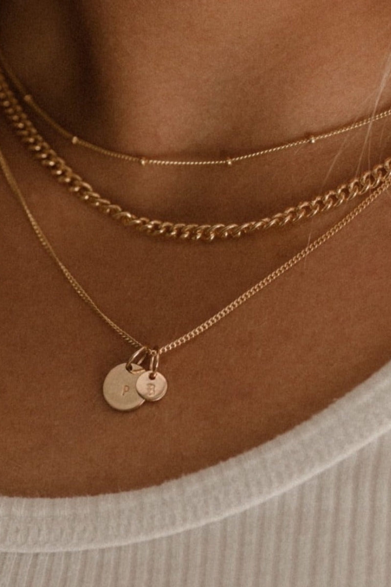 A Fine Curb Chain is layered with a Keeping it Personal Necklace with mini solid gold initial pendant