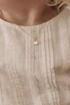 A young girl wears the Petite 9ct Gold Initial Pendant on a ball chain necklace in gold vermeil