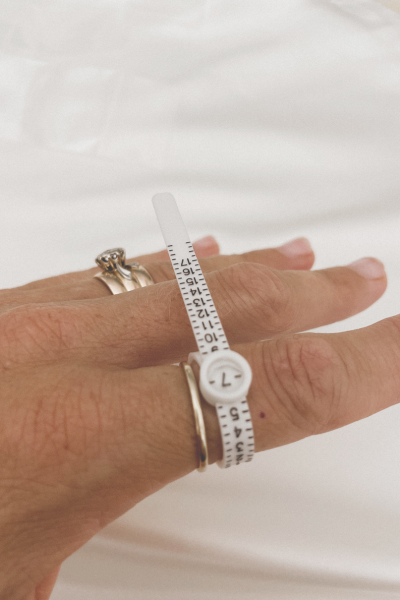 A ring sizer on a pointer finger alongside a size 7 ring showing that it shows the true ring size.