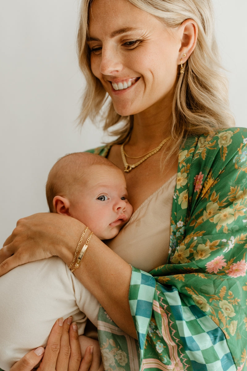 Mum and baby wear matching engraved gold jewellery—personalised bracelet designed for babies, kids, and adults by Bluebird Jewellery.