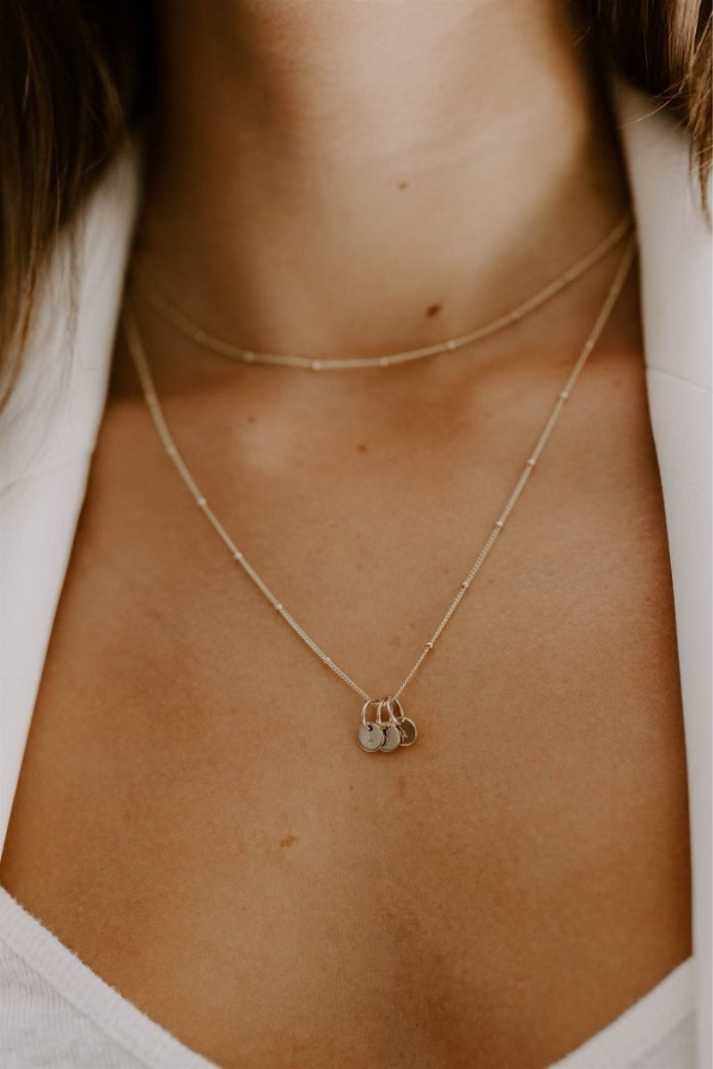 The 35+5cm Gold Ball Chain Necklace is layered with the 45+5cm necklace with Mini Initial Pendants.