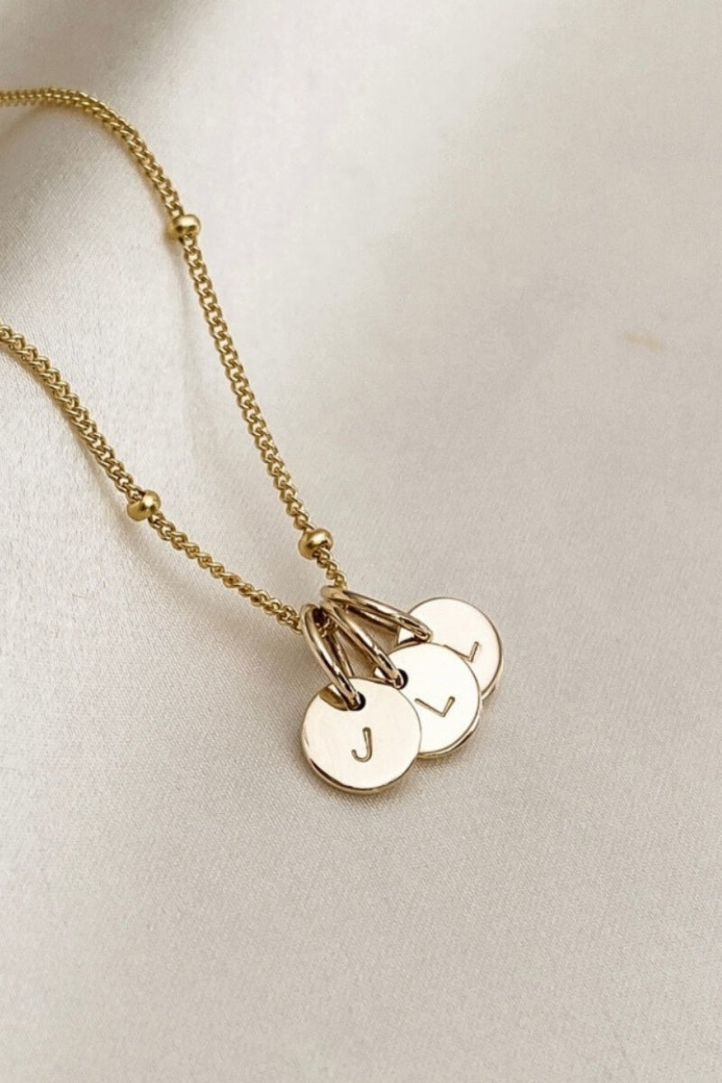 A close up of the solid 9ct gold initial pendants on a gold plated ball chain necklace