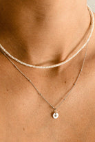 A woman is wearing a Freshwater Pearl necklace layered with a Vintage Pearl Necklace. The two necklaces both feature natural pearls and look both modern and elegant on the woman’s neckline.