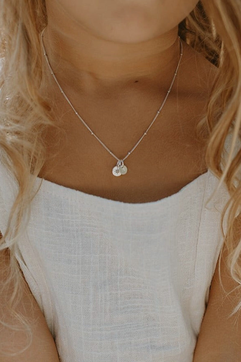 A close up look at the Vintage Pearl necklace with Petite initial pendant in sterling silver that a young girl is wearing. She wears the 35cm length necklace. 