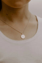 A beautiful close up image of a young girl wearing a persoanlised necklace with her initial engraved on the front of the softly textured pendant.