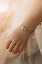 A delicate close-up of a child wearing a  rose gold Bracelet featuring a mermaid shell and initial pendant, designed as a meaningful keepsake.