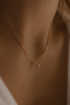 A woman wearing the Lumé Necklace by Bluebird Jewellery, a delicate gold pendant designed to reflect light and celebrate life’s special milestones.