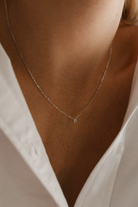 A close-up photo of a woman wearing the Lumé Necklace by Bluebird Jewellery, inspired by the French word for ‘light,’ crafted as a radiant symbol of warmth and kindness.