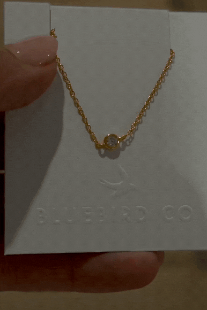 a close up of a gold bracelet with a cubic zirconia set within the chain.