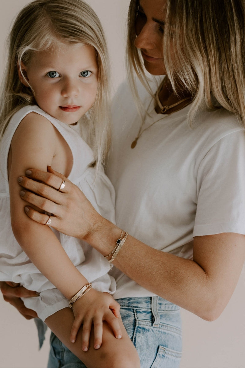 A mother and daughter are wearing matching Bluebird Co Signature Bracelets in Gold Vermeil with personalised engraving.