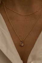 A woman wearing a fine curb chain necklace with the Mini Rectangular Pendants Bluebird Jewellery features gentle curves and a luxe, modern silhouette. Personalised with your chosen letter, it embodies feminine elegance and can be worn beautifully on any necklace, bracelet, or anklet chain.