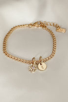 A lace chain bracelet with a daisy pendant and a classic round Petite Gold Vermeil Initial Pendant from Bluebird Jewellery, personalised with your chosen letter and designed to be worn elegantly on any necklace, bracelet, or anklet chain.