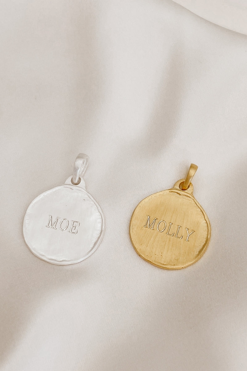 A silver and gold Petite Pet Pendnat sit alongside one another with personalised engraving on each.