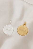 A silver and gold Petite Pet Pendnat sit alongside one another with personalised engraving on each.