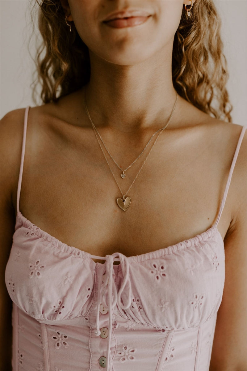 A teenage girl wears the Petite Darling Necklace and Darling Necklace together with the  shorter necklace being the Petite Darling Necklace.  Her You Are Loved earrings compliment the two necklaces.