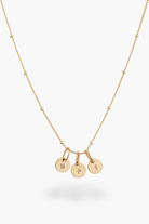 Gold necklace with three round solid gold pendants on a white background